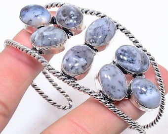 Peut inclure: Bracelet en argent avec six pierres d'agate dendritique ovales. Les pierres sont un mélange de blanc et de gris avec des motifs dendritiques noirs. Le bracelet a une bande en argent torsadée.