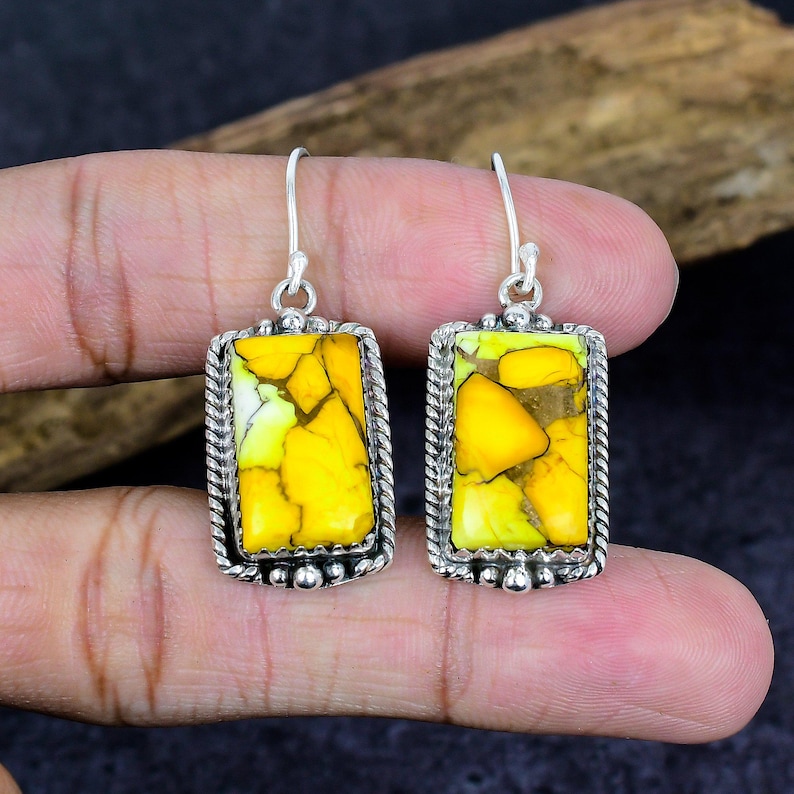 May include: A pair of silver earrings with rectangular yellow and green stone inlays. The stones have a unique, cracked appearance. The earrings are framed with a twisted rope design and small silver beads.