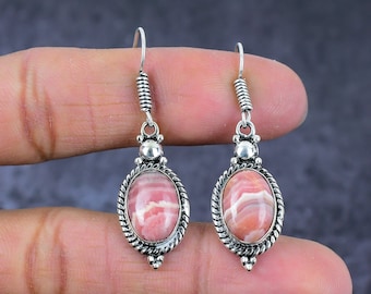 May include: A pair of silver dangle earrings with pink and white striped oval-shaped stones.