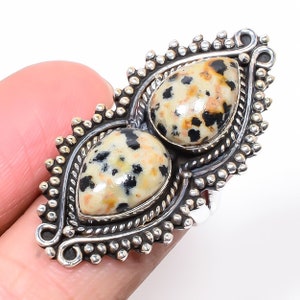 Peut inclure: Une bague en argent avec deux pierres de jaspe dalmatien serties dans un design orné détaillé.