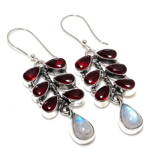 May include: Silver dangle earrings with red gemstone drops and a pear-shaped moonstone pendant.
