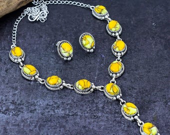 May include: A silver necklace and matching earrings set. The jewellery features oval-shaped yellow and green stones set in silver metal. The necklace has a chain and a pendant design.