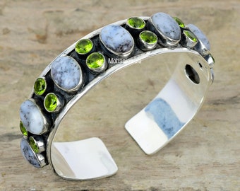 Peut inclure: Bracelet en argent avec un rang de pierres ovales blanches et grises et des pierres précieuses vertes. Le bracelet est ouvert et possède un fermoir à charnière.