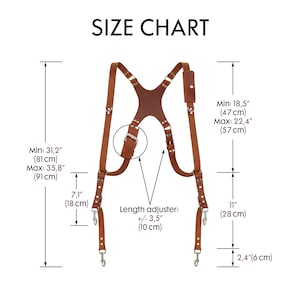 May include: A brown leather suspender set with silver-tone metal hardware. The image includes a size chart with measurements in inches and centimeters, detailing the dimensions of the suspenders, including the length and width.