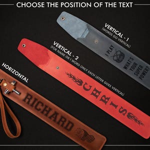 May include: Leather accessories with text options. A brown leather strap with "RICHARD" engraved horizontally. A red strap with "CHRIS" engraved vertically. A gray strap with "I PLAY WHAT'S YOUR SUPER POWER?" engraved vertically.