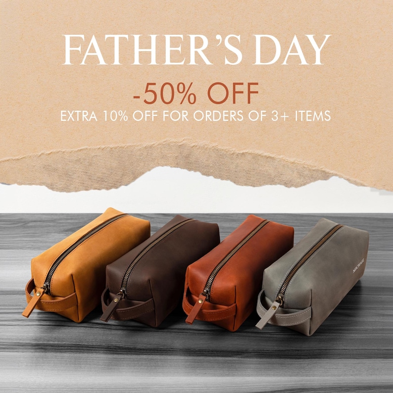 May include: Four leather toiletry bags in shades of tan, brown, and gray are displayed on a wooden surface. Each bag has a zipper closure and a small handle. The text "FATHER'S DAY -50% OFF" is at the top of the image.