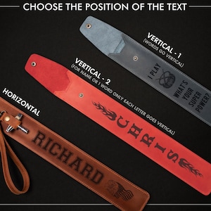 May include: Leather accessories with text options. The image shows three leather items: a brown one with "RICHARD" engraved, a red one with "CHRIS" vertically, and a gray one with "I PLAY" and "WHAT'S YOUR SUPER POWER?" vertically. The text options are for personalization.