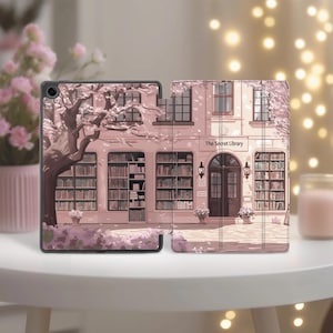May include: A tablet case featuring an illustration of a library with a cherry blossom tree. The building is pink with the text "The Secret Library" above the door. The case is open, revealing the tablet screen.