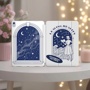 May include: White iPad case with a blue and white illustration. The left side depicts a night sky scene through an arched window. The right side shows a woman reading with the text "LEAVING REALITY ENTERING FICTION".