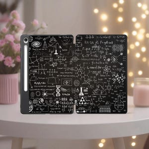Może przedstawiać: Czarny futerał na tablet z białymi ilustracjami wzorów naukowych, diagramów i równań. Etui jest otwarte, ukazując szczegółowe wzory po obu stronach. Dołączony jest biały rysik.