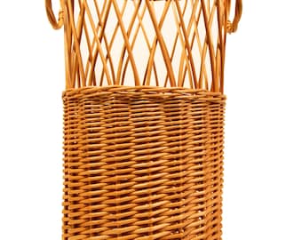 Puede incluir: Un soporte para paraguas de mimbre tejido natural con dos asas. El soporte es alto y cilíndrico, con un patrón tejido.