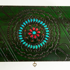 May include: A green wooden box with a decorative floral design in turquoise, pink, and brown. The box has a keyhole and a small key.
