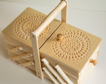 May include: A wooden box with a hinged lid and a carved floral design. The box has a handle and is divided into compartments.