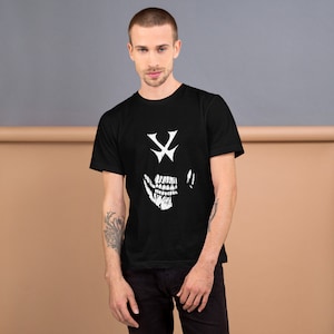 Puede incluir: Una camiseta negra con un gráfico de calavera blanca. La calavera tiene una cruz por ojos y una amplia sonrisa con dientes.