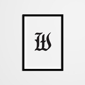 Puede incluir: Impresión enmarcada en blanco y negro de la letra W en una fuente gótica.