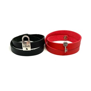 May include: Two leather bracelets, one black with a silver padlock charm that says "LOVE" and one red with a silver key charm.