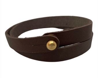 May include: A brown leather wrap bracelet with a gold metal button closure.