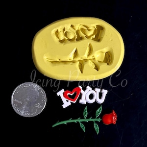 May include: A yellow silicone mold with a rose design and the word "Love". Also, a red and white "I Love You" decoration and a red rose with green stem and leaves. A quarter is included for size reference.