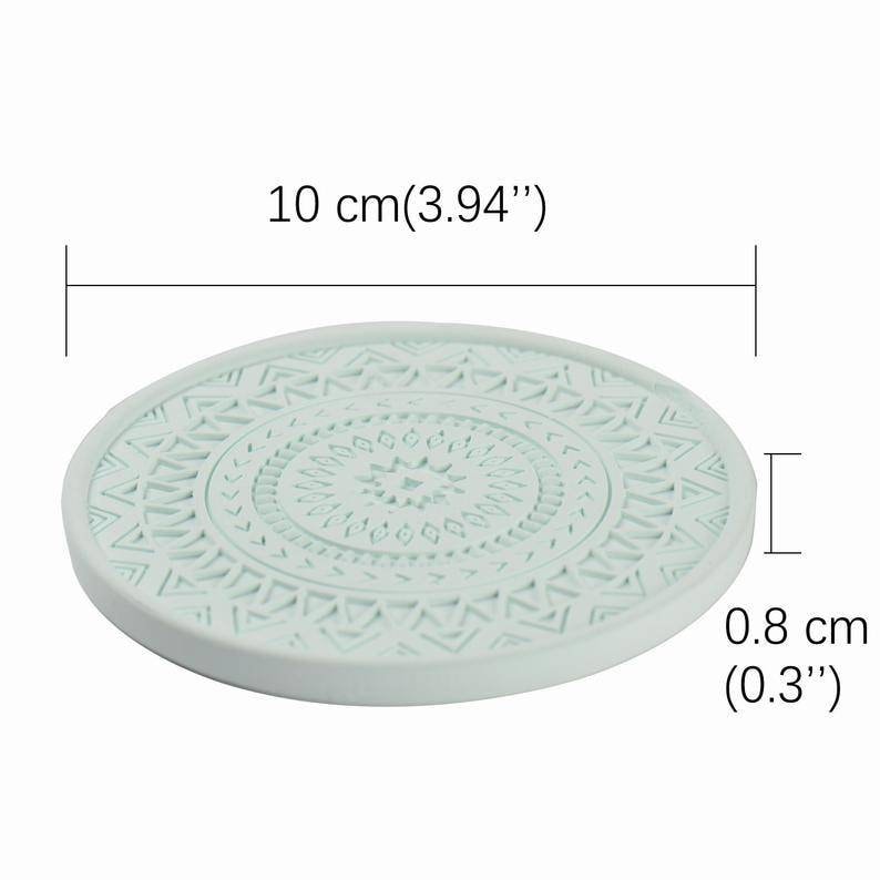 May include: A light blue round coaster with a geometric pattern. The coaster measures 10 cm in diameter and 0.8 cm in height.