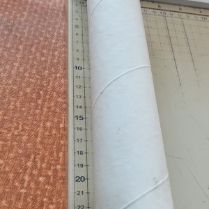 Puede incluir: Un tubo de cart&oacute;n blanco que mide aproximadamente 63,5 cm de largo. El tubo est&aacute; sobre una superficie blanca con una regla a su lado. La regla est&aacute; marcada con n&uacute;meros del 3 al 26.