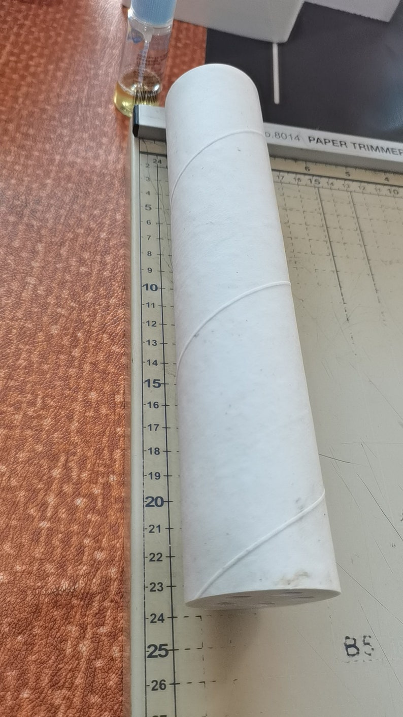 Puede incluir: Un tubo de cart&oacute;n blanco que mide aproximadamente 63,5 cm de largo. El tubo est&aacute; sobre una superficie blanca con una regla a su lado. La regla est&aacute; marcada con n&uacute;meros del 3 al 26.