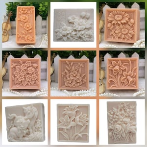 May include: A collection of intricately carved soaps featuring floral and unicorn designs. The soaps are various shapes, including rectangular and square, and are in shades of peach and cream. Some soaps feature detailed flower arrangements.