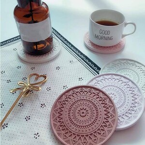 May include: Set of six colourful coasters with geometric patterns. The coasters are made from a durable material and feature a variety of colours, including pink, purple, and green. The coasters are ideal for protecting your furniture from heat and spills.