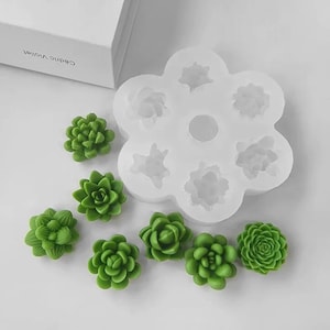 May include: A silicone mould shaped like a flower with six cavities for making succulent-shaped decorations. There are eight green succulent-shaped decorations next to the mould.