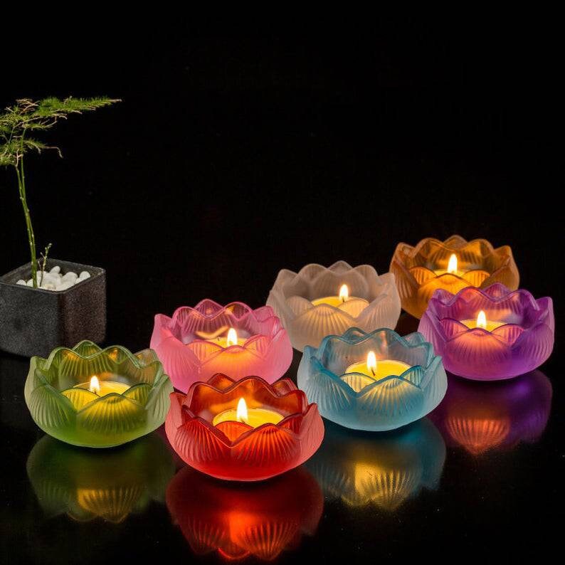 May include: Eight lotus-shaped candle holders in various colors, including pink, purple, blue, green, and red. Each holder has a small candle inside, creating a warm glow.