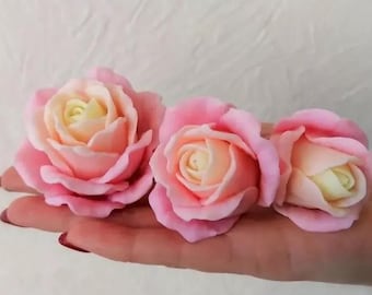 May include: Three pink and white roses with a yellow center. The roses are made of a soft, pliable material and have a realistic appearance.