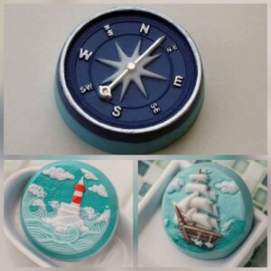 Op de afbeelding: Drie ronde zeepjes met een nautisch thema. De eerste zeep is blauw met een kompasontwerp. De tweede zeep is turquoise met een witte vuurtoren en golven. De derde zeep is turquoise met een wit zeilschip en golven.