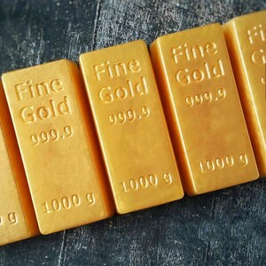 Może przedstawiać: Cztery sztabki złota z nadrukiem "Fine Gold 999.9" i "1000 g".