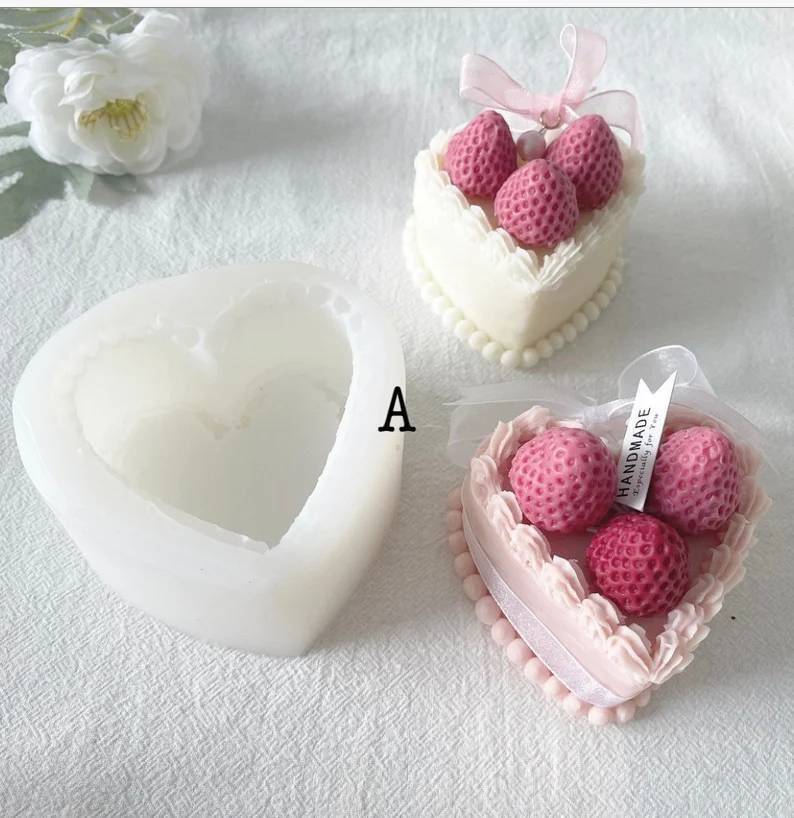 May include: A white silicone heart-shaped mold with a pink heart-shaped cake with white frosting and three red strawberries on top. The cake is decorated with white pearls around the edge. The cake is labeled "Handmade Especially for You".