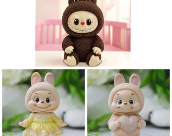 May include: A collection of whimsical bunny figurines. One is brown with a toothy grin, another wears a yellow dress, and the last holds a heart. Each has a smiling face and bunny ears, perfect for a nursery or Easter decor.