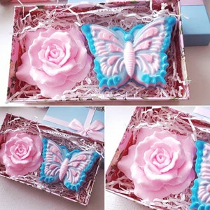 May include: Two handmade soap bars in a gift box. One soap bar is shaped like a pink rose and the other is shaped like a blue butterfly.