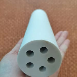 Puede incluir: Un difusor de cer&aacute;mica blanco con cinco agujeros en la parte inferior. El difusor es cil&iacute;ndrico y tiene una superficie lisa.