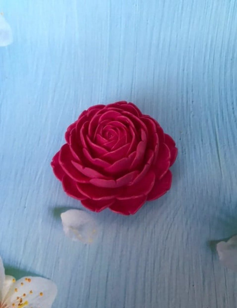 May include: A single, large, pink, fabric rose flower. The rose is made of many layers of petals and has a realistic appearance.