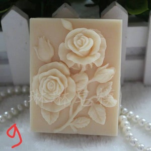 May include: A white silicone mold with a raised design of a rose bouquet. The mold is rectangular and has a smooth surface.