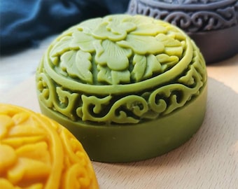 May include: Three round, decorative soaps with intricate floral designs. The soaps are green, purple, and yellow.