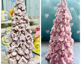 May include: Two pink, detailed, Christmas tree-shaped decorations. The trees are decorated with bows, ornaments, and other festive details.