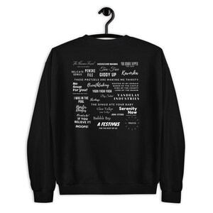 Peut inclure: Sweat-shirt noir avec du texte blanc comportant une variété de phrases et de mots, notamment "Hoochie Mama", "Giddy Up", "Kavorka", "Yada Yada Yada", "The Dingo Ate Your Baby", "Serenity Now", "A Festivus for the Rest of Us", et "Moops!"
