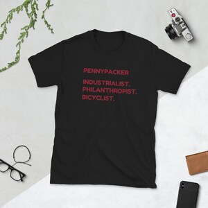 May include: Black t-shirt with the text "PENNYPACKER INDUSTRIALIST. PHILANTHROPIST. BICYCLIST." printed in red.