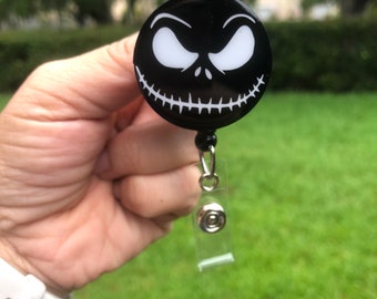 Puede incluir: Portagafete retráctil negro con un diseño de cara de Jack Skellington blanco.