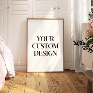 May include: A framed print with the text "YOUR CUSTOM DESIGN" stands on a wooden floor. The print is in a room with a bed, white closet doors, and a vase of pink flowers. The room has a natural light.