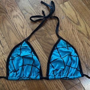 May include: A blue and black bikini top with a geometric pattern. The top has adjustable straps and a tie closure at the back.