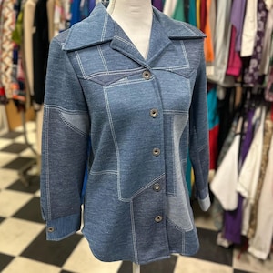 May include: A blue denim shirt with a patchwork design and button fastening. The shirt has a collar and long sleeves.