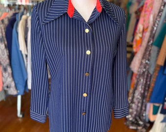May include: A blue and white striped long-sleeved shirt with a red collar and gold buttons.