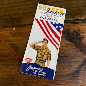 May include: A vintage Golden Jamboree Boy Scouts of America souvenir booklet from July 22-28, 1960, in Colorado. The cover features a saluting scout in uniform, the American flag, and the Conoco logo.