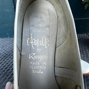 Pu&ograve; includere: Primo piano dell'interno di una scarpa bianca con il testo "Amalfi by Rangoni Made in Florence Italy" stampato sulla soletta.