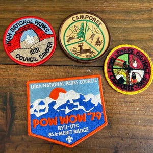 Puede incluir: Cuatro parches bordados vintage. Uno rojo y beige dice "Utah National Parks Council Camper 1981". Otro es redondo con un ciervo y dice "Camporee". Un tercer parche dice "Lenape District Camporee 1964". El último parche dice "Pow Wow 79 BYU-UTC BSA Merit Badge."